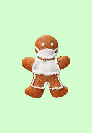 Cute gingerbread man with protective face mask, isolated, green background.