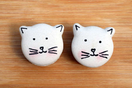 Cute macarons in a shape of cats on wooden board, top view. Creative bakingの写真素材