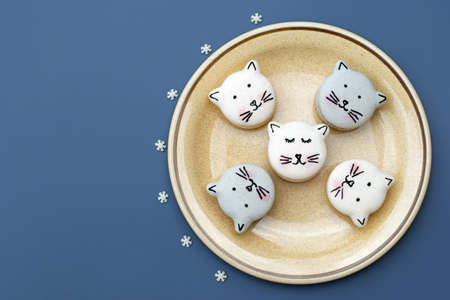 Cute macarons in a shape of cats on a plate, small sugar snowflakes around, top view, copy space. Christmas or winter time. Creative bakingの写真素材