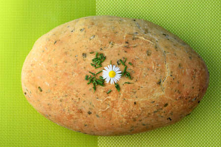 Homemade, freshly baked chive bread, garnished with chopped chives and daisy flowerの写真素材
