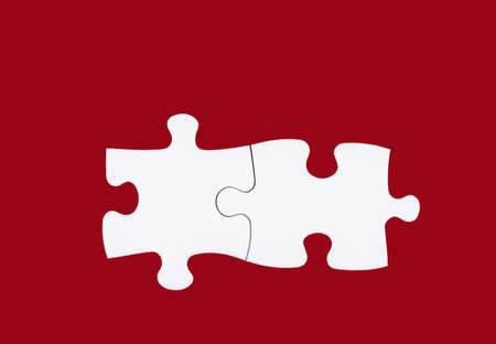 Two white puzzle pieces isolated on red background. Concept of teamwork, solving problems