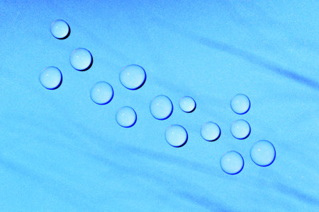 Sparkling water drops on blue plastic surface, copy space for text