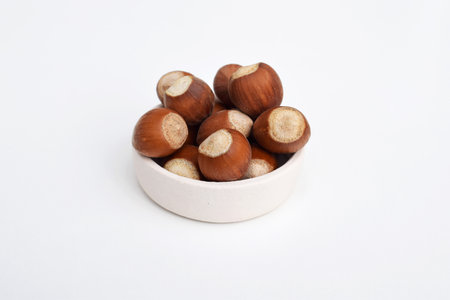Hazelnuts in shell in a small bowl, white backgroundの写真素材