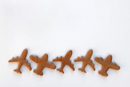 Undecorated gingerbread cookies in a shape of airplanes, white background, copy space for textの写真素材
