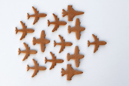 Undecorated gingerbread cookies in a shape of airplanes, white background