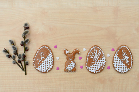 Romantic decorated Easter gingerbread cookies in a shape of egg and bunny, with willow twigs and...