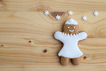 Smiling gingerbread woman on a wooden background with snowflakes, copy space for textの写真素材
