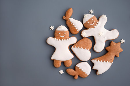 Decorated gingerbread cookies of various shapes on a gray background with snowflakes, copy space for...