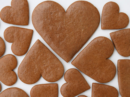 Undecorated heart-shaped gingerbread cookies in three sizes on a white backgroundの写真素材