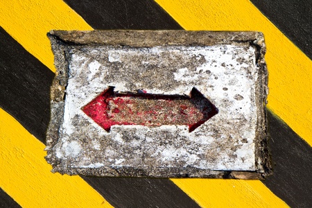 Red arrow on the yellow and black strip backgroundの写真素材