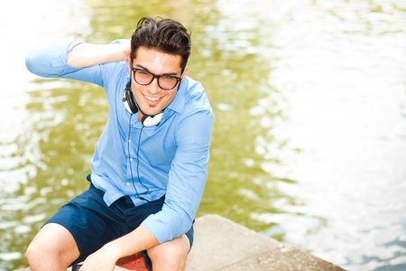 handsome man wearing glasses talking on the phone and smiling by the river の写真素材
