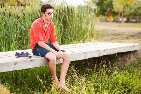 handsome man standing on a bridge by the lakeの写真素材