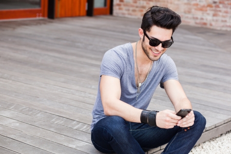 attractive young male model texting on a smartphoneの写真素材
