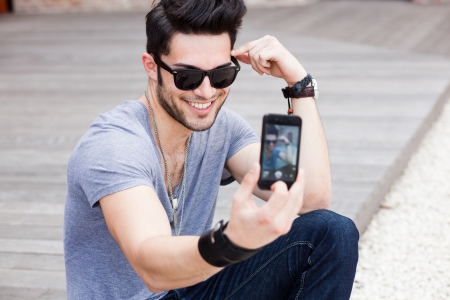 young male model photographing himself with a smartphoneの写真素材