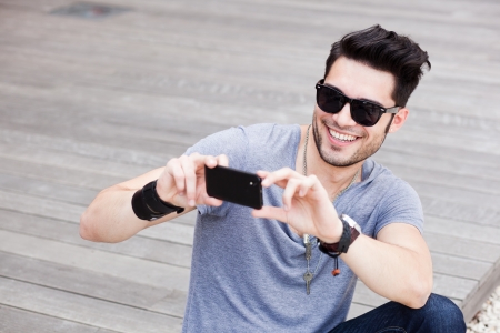 attractive man taking photos with a black smartphoneの写真素材