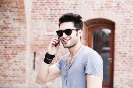 attractive young male model posing outdoors in blue shirt and sunglassesの写真素材