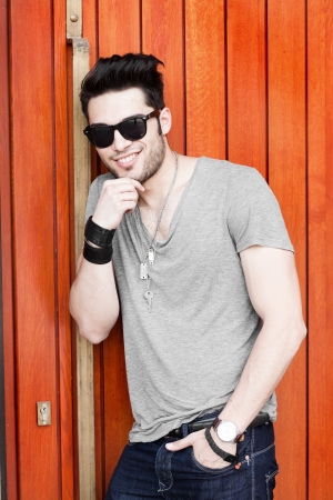 attractive young male model posing outdoors in gray shirt and sunglassesの写真素材