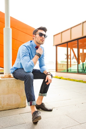 attractive young male model posing outdoors in blue shirt and sunglassesの写真素材
