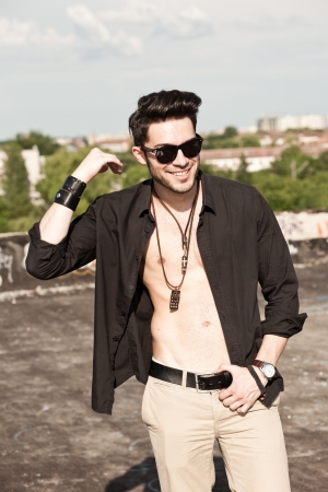 attractive young male fashion model, unbuttoned shirt smiling outdoorの写真素材