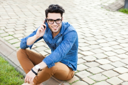 handsome young man talking on a smartphone outdoorsの写真素材