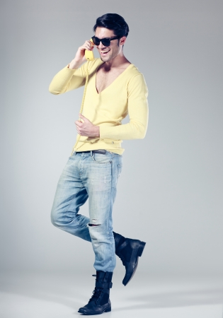 attractive man smiling talking on a yellow phoneの写真素材