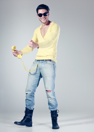 funny call center guy with hipster glasses and colouful phonesの写真素材