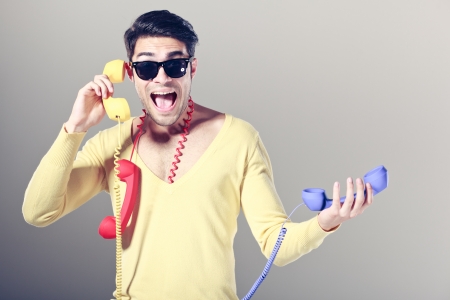 funny call center guy with hipster glasses and colouful phonesの写真素材