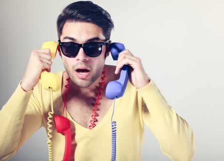 funny call center guy with hipster glasses and colouful phonesの写真素材