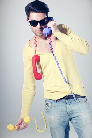 funny call center guy with hipster glasses and colouful phonesの写真素材