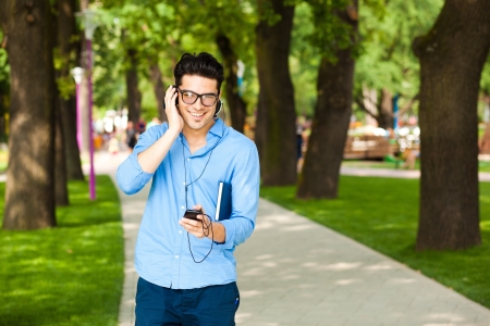 handsome man smiling and listening to music in the park の写真素材