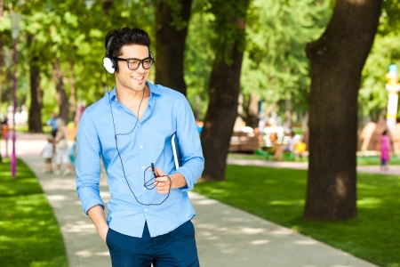 handsome man looking at his smartphone and listening to music in the park の写真素材