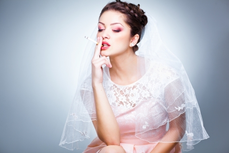 portrait of beautiful bride smoking a cigarette - funny pictureの写真素材
