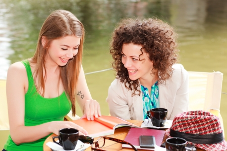 Two beautiful women chatting over a coffee at the river side terraceの写真素材