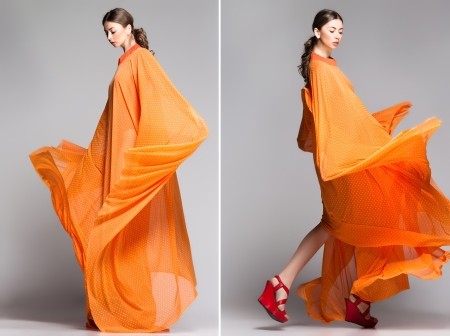 beautiful woman in long orange dress posing dynamic in the studioの写真素材