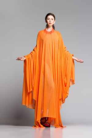 beautiful woman in long orange dress posing dynamic in the studioの写真素材