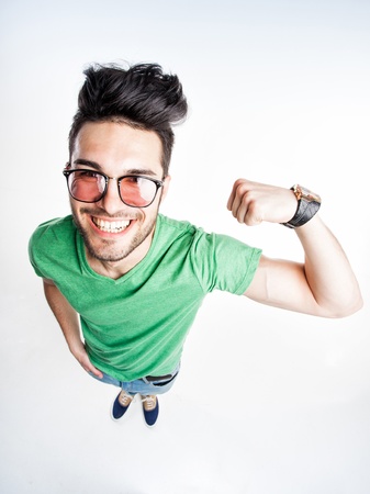 funny handsome man with hipster glasses showing muscles - wide angle shotの写真素材