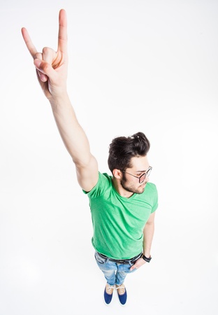 funny handsome man with hipster glasses showing "we rock" and smiling  - wide angle shotの写真素材