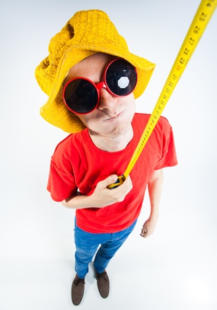 funny guy dressed colorful and crazy holding a measuring tapeの写真素材