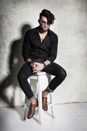 sexy fashion man model dressed casual posing dramatic against grunge wallの写真素材