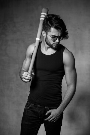 sexy fashion man model with a baseball bat posing dramatic against grunge wallの写真素材