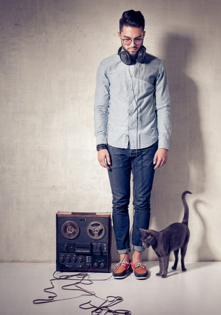 handsome man and cat listening to music on a magnetophone against grunge wallの写真素材