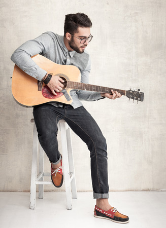 handsome man playing an acoustic guitar against grunge wallの写真素材