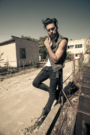 handsome man model dressed punk, hipster posing dramatic in grunge locationの写真素材