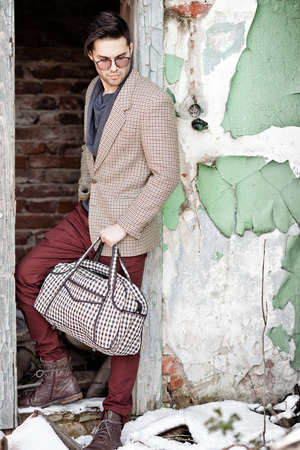 sexy fashion man model dressed vintage elegant holding a bag posing outdoorの写真素材