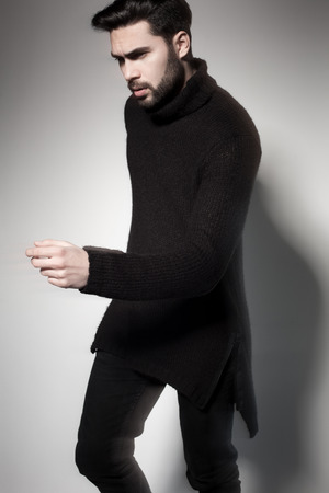 sexy fashion man model in black sweater, jeans and boots posing dramaticの写真素材