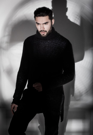 sexy fashion man model in black sweater, jeans and boots posing dramaticの写真素材