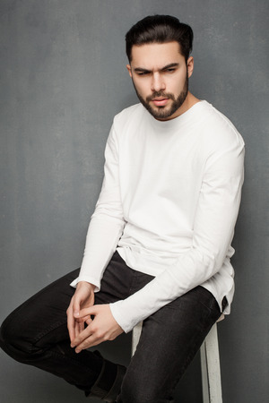sexy fashion man model in white sweater, jeans and boots posing dramaticの写真素材