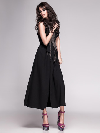 sexy slim woman model with long legs in black dress and high heels posingの写真素材