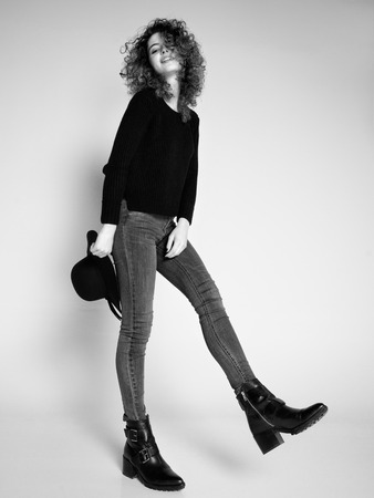 pretty woman posing in denim pants and boots and black hatの写真素材