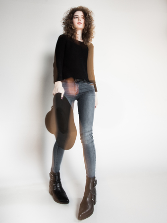 pretty woman posing in denim pants and boots and black hat - intentional motion blurの写真素材